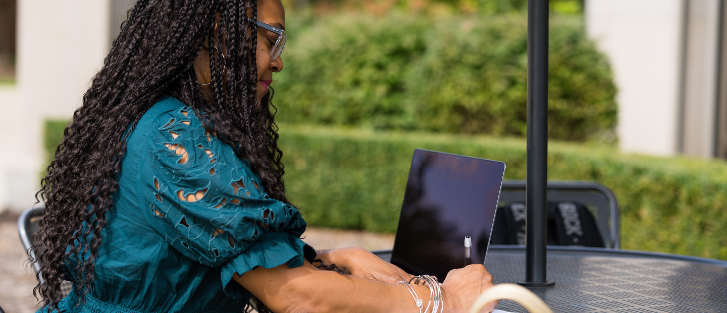 Application Deadlines Banner Woman typing on a laptop outside the Oakland Center