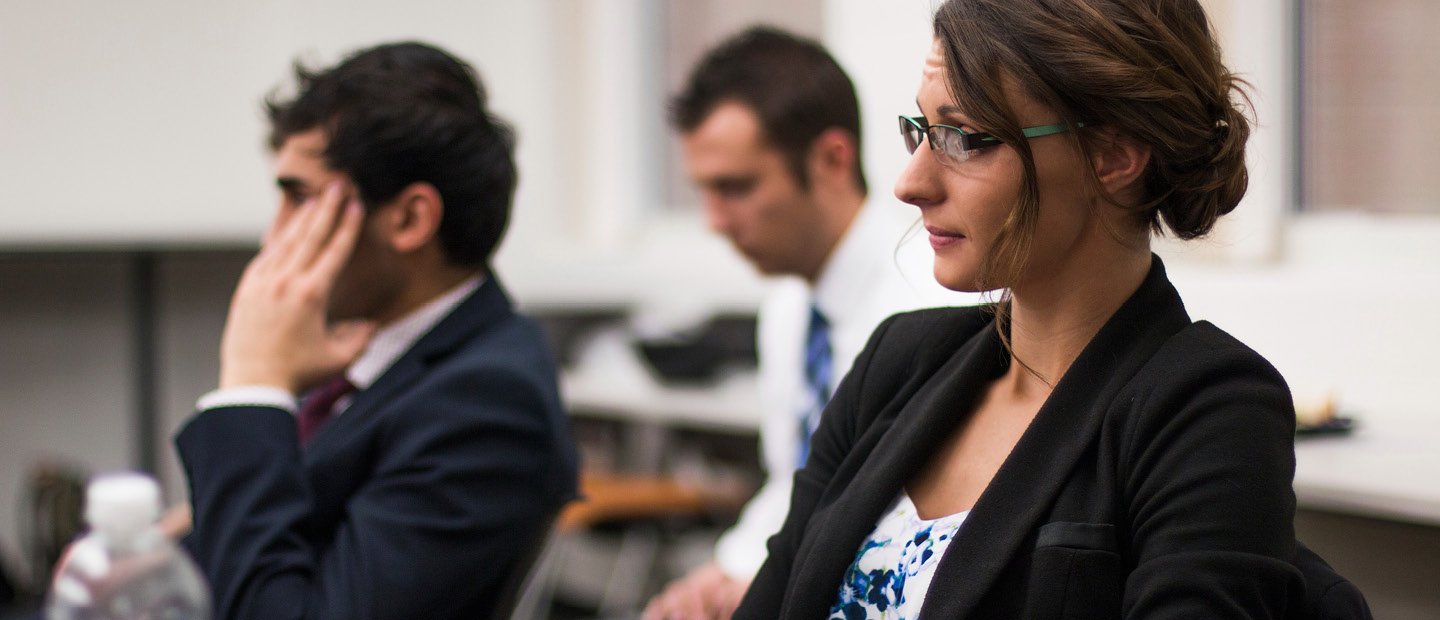 Three adults in business attire, seated at desks. Three adults in business attire, seated at desks.