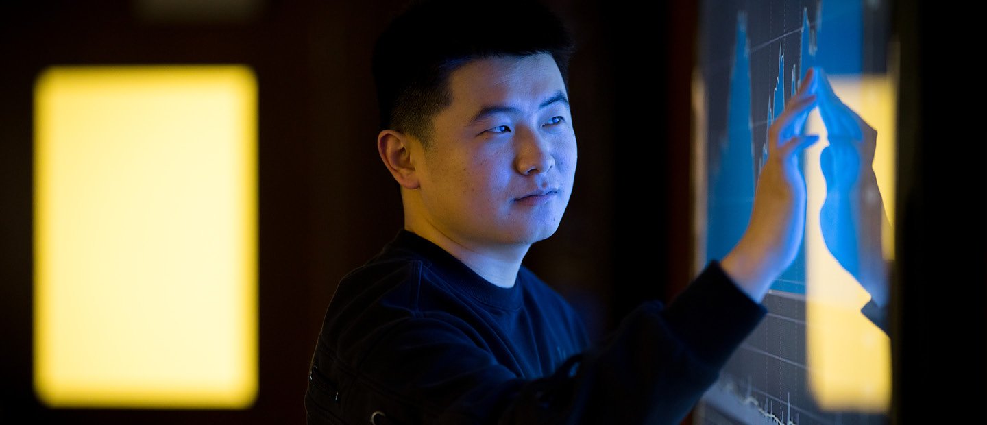 A young man touching a screen with a blue graph on it. A young man touching a screen with a blue graph on it.