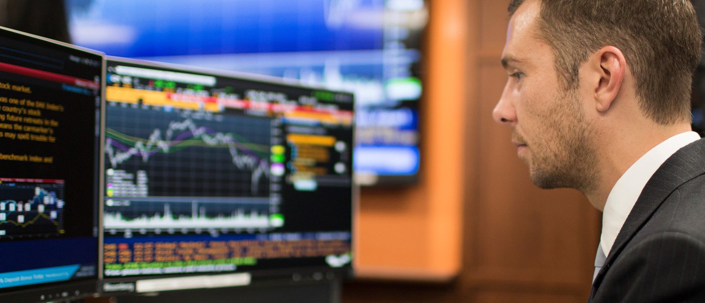 SBA-22398_Finance2.jpg A man seated with two computer monitors that are displaying colorful graphs and data.