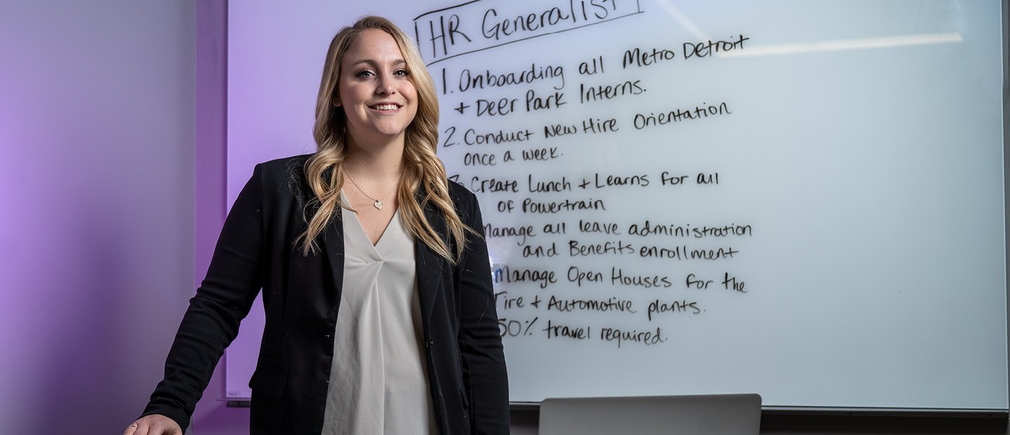 A woman standing in front of a white board with A young woman standing in front of a white board with