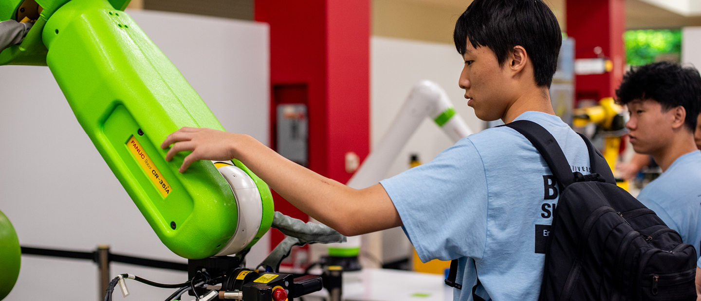 Summer Camps Students working with robotic machines in a lab.