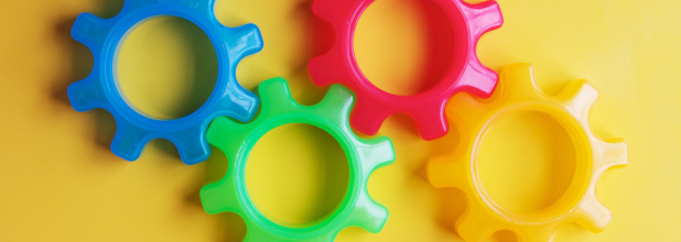 A collection of bright plastic gears set against a cheerful yellow backdrop