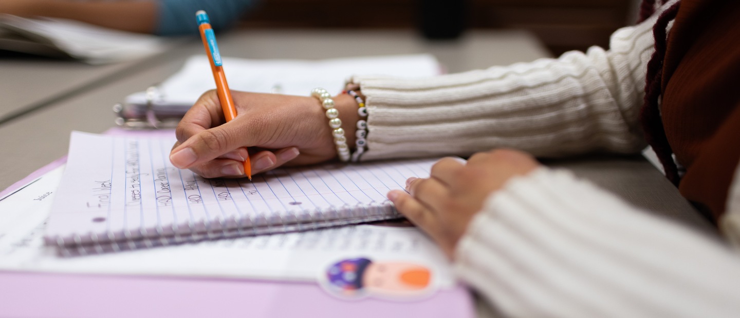 Teaching Resources Banner A closeup of hand holding pencil writing in a notebook.