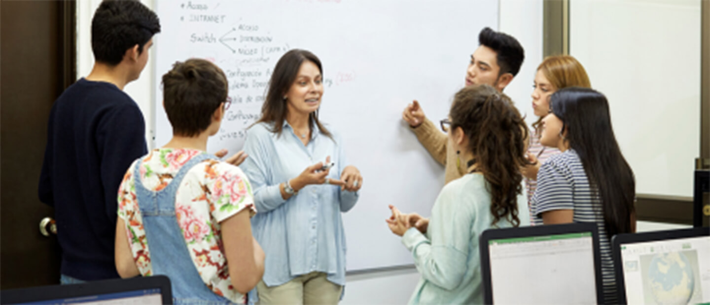 professor and students discussing in front of a white board.