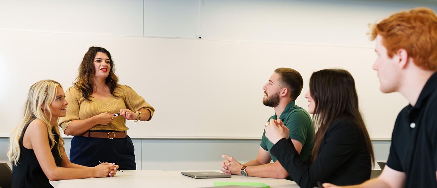 CJ - Advising page Banner A professor standing in front of a table of students