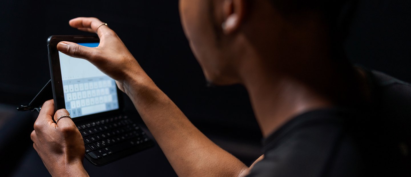 Communication, M.A. Banner A person typing on a small tablet.