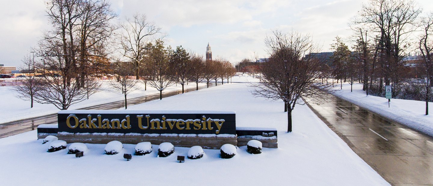 20161212_Winter_17.jpg An Oakland University sign at the entrance to campus with snow on the ground.