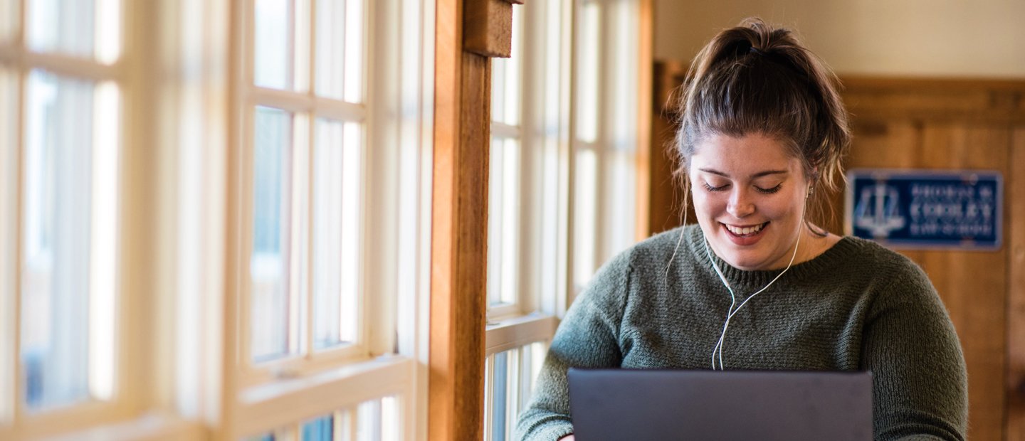 DegreeEvaluation.jpg woman wearing headphones looking down at an open laptop