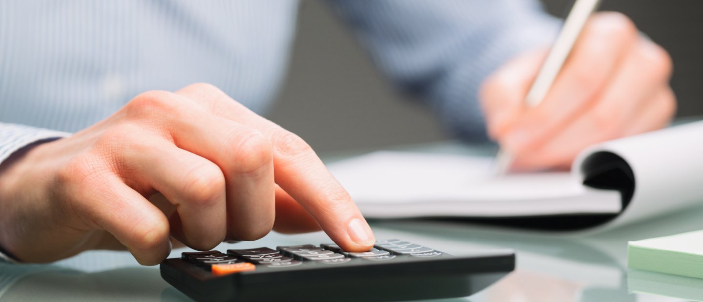 UCM-17181_Banners_financialassistance.jpg Hands writing in a notebook and using a calculator