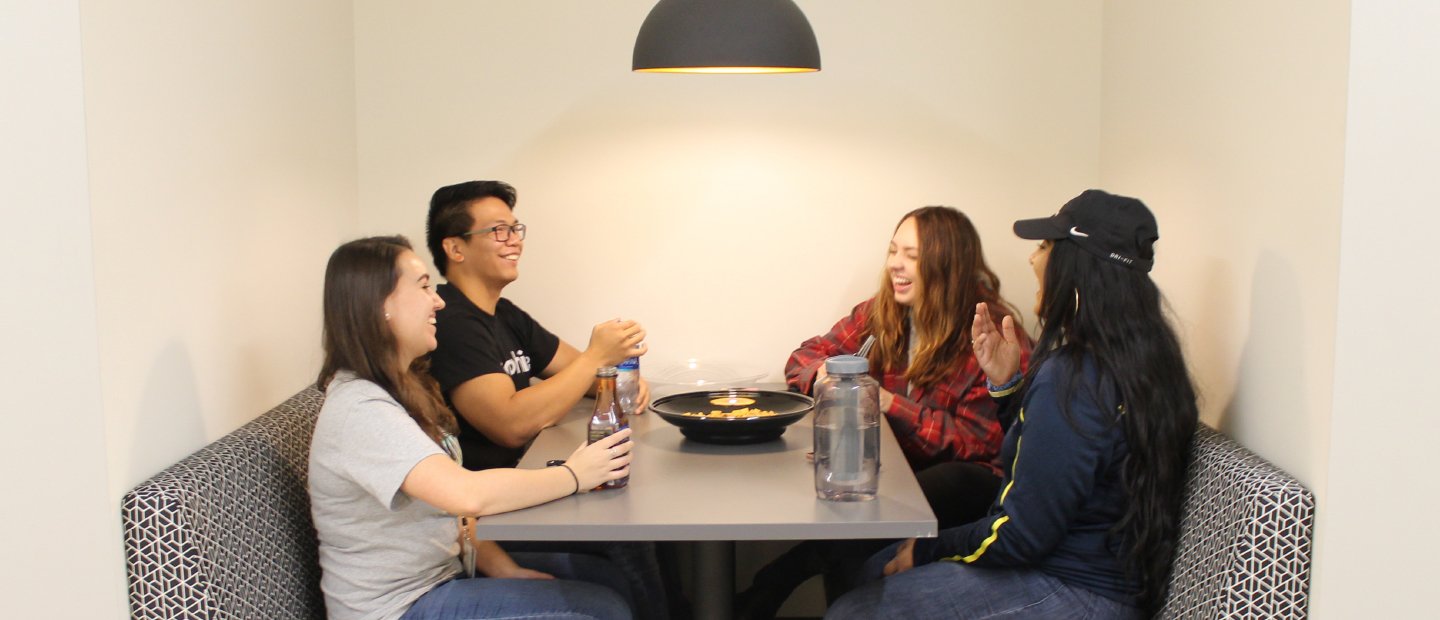 Local O U Discounts Banner four students seated at a table with beverages and a bow of food in the middle