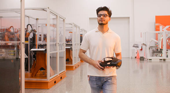 Young man walking down a hallway carrying electrical equipment.