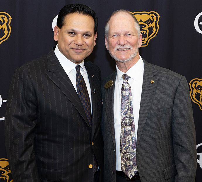 Dr. Ball and Dr. Nandi smile in front of an OU background