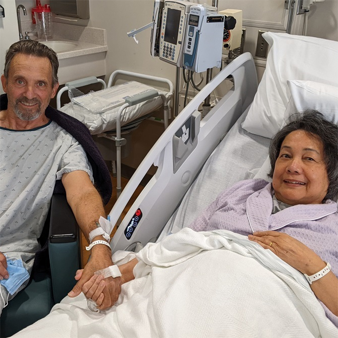 A woman in a hospital bed, with a man sitting next two her