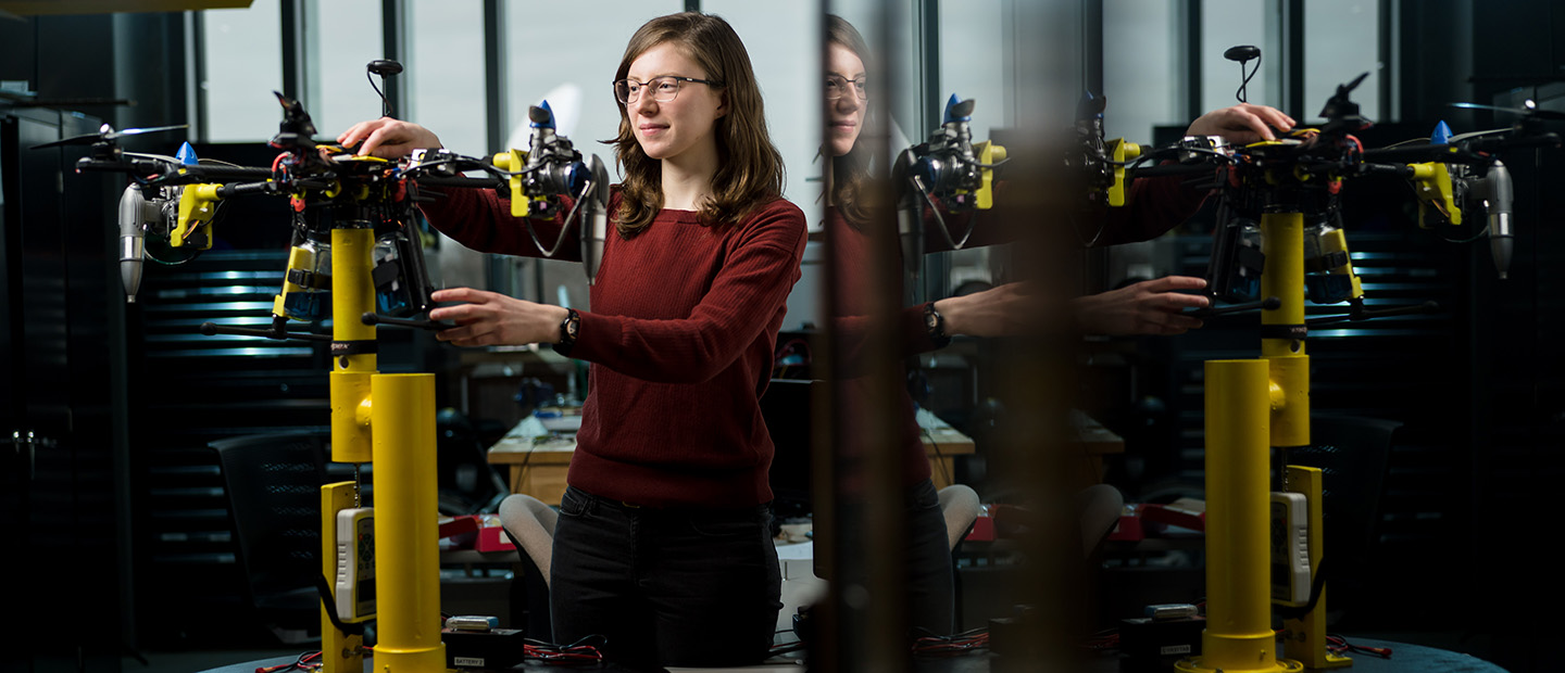 Student Research/Funding Opportunities Banner A young woman working with a mechanical device in a lab.