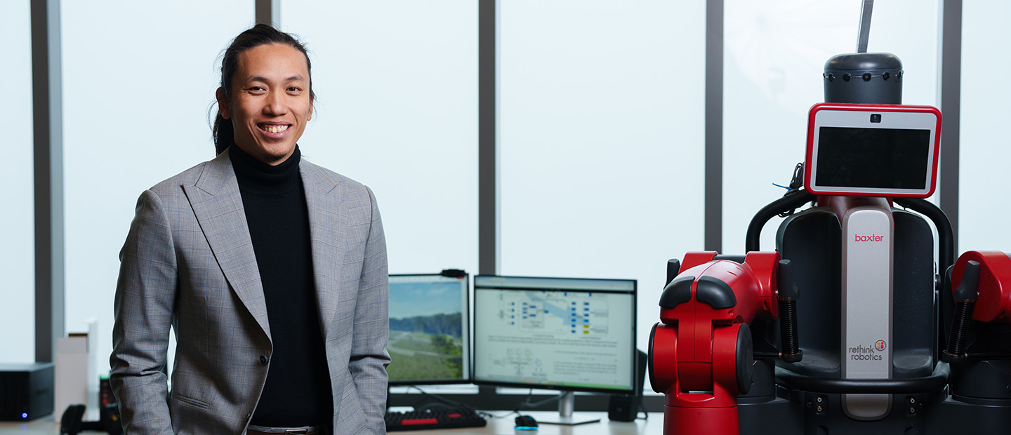 A professor standing next to a robot