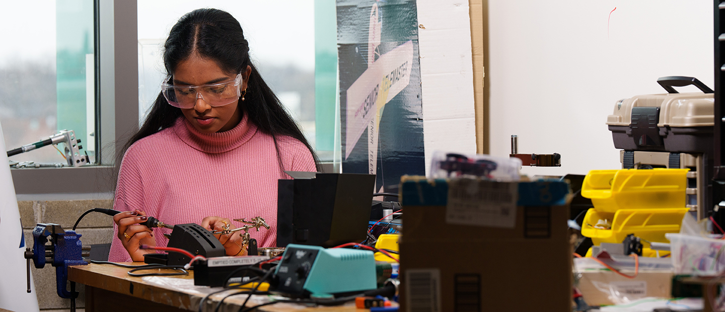 SECS Department Undergraduate Programs EE Banner A young woman working on electrical equipment