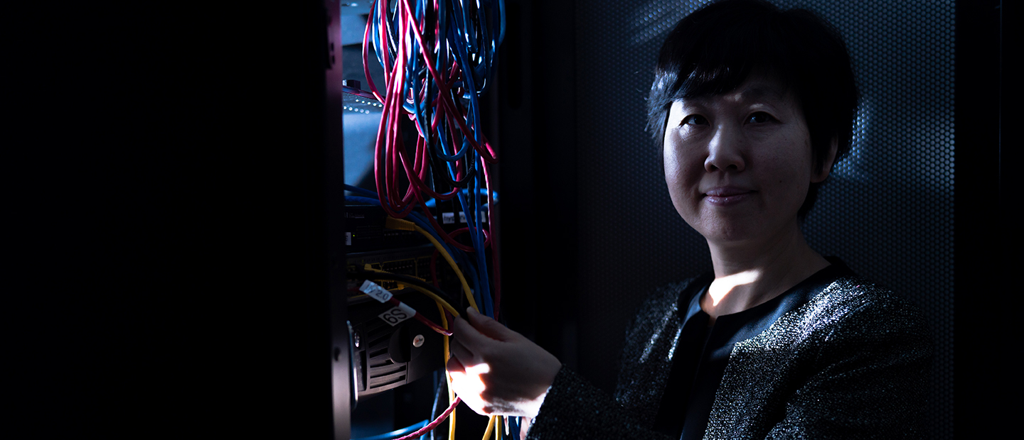 SECS Master of Science Programs Cybersecurity Banner A woman holding the wires from a computer