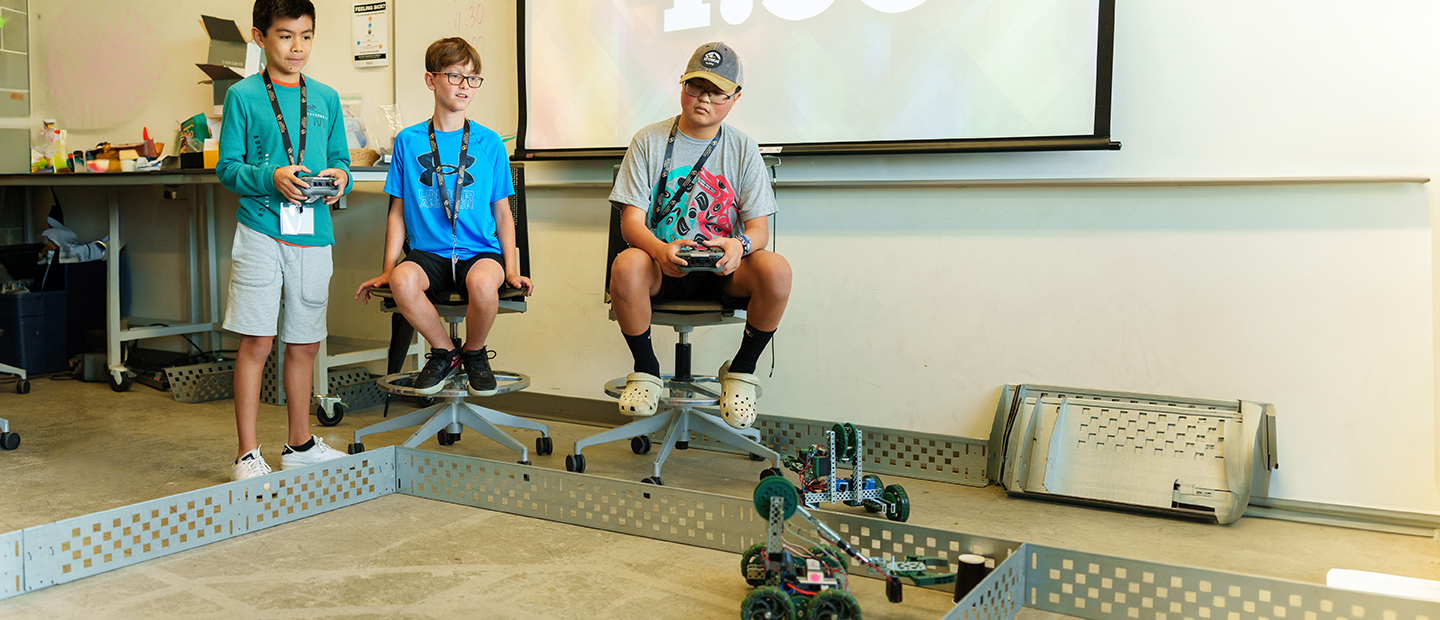 SECS - Outreach Programs Banner Three young boys using remote controlled robots