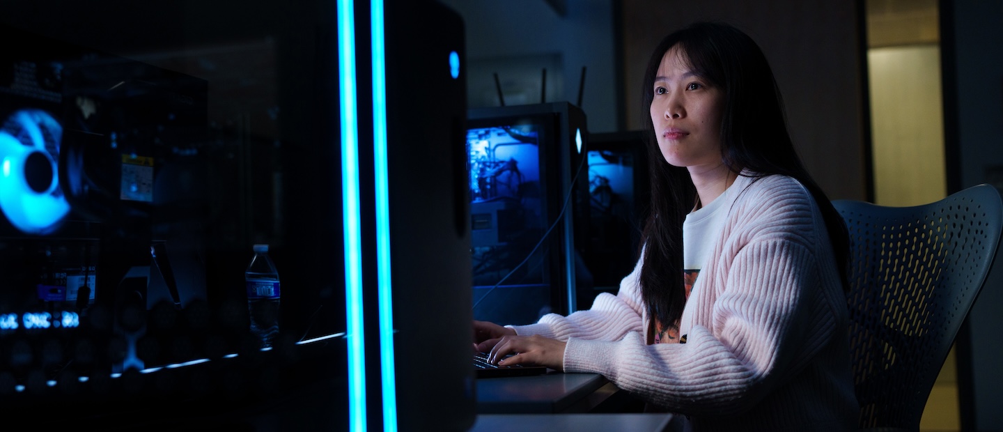 Undergraduate Programs Cyber Security A woman in a dark computer lab