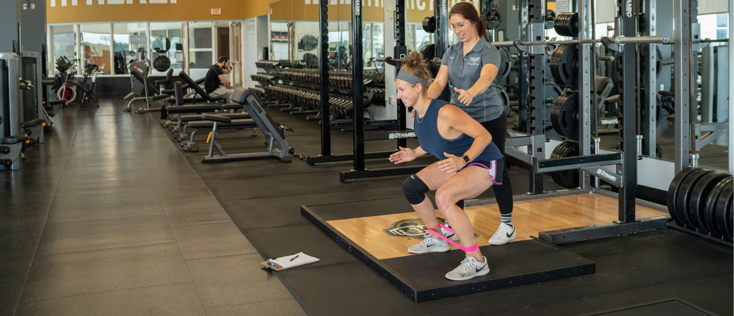 EXS Certificate.png A personal trainer guiding a client in a squat.