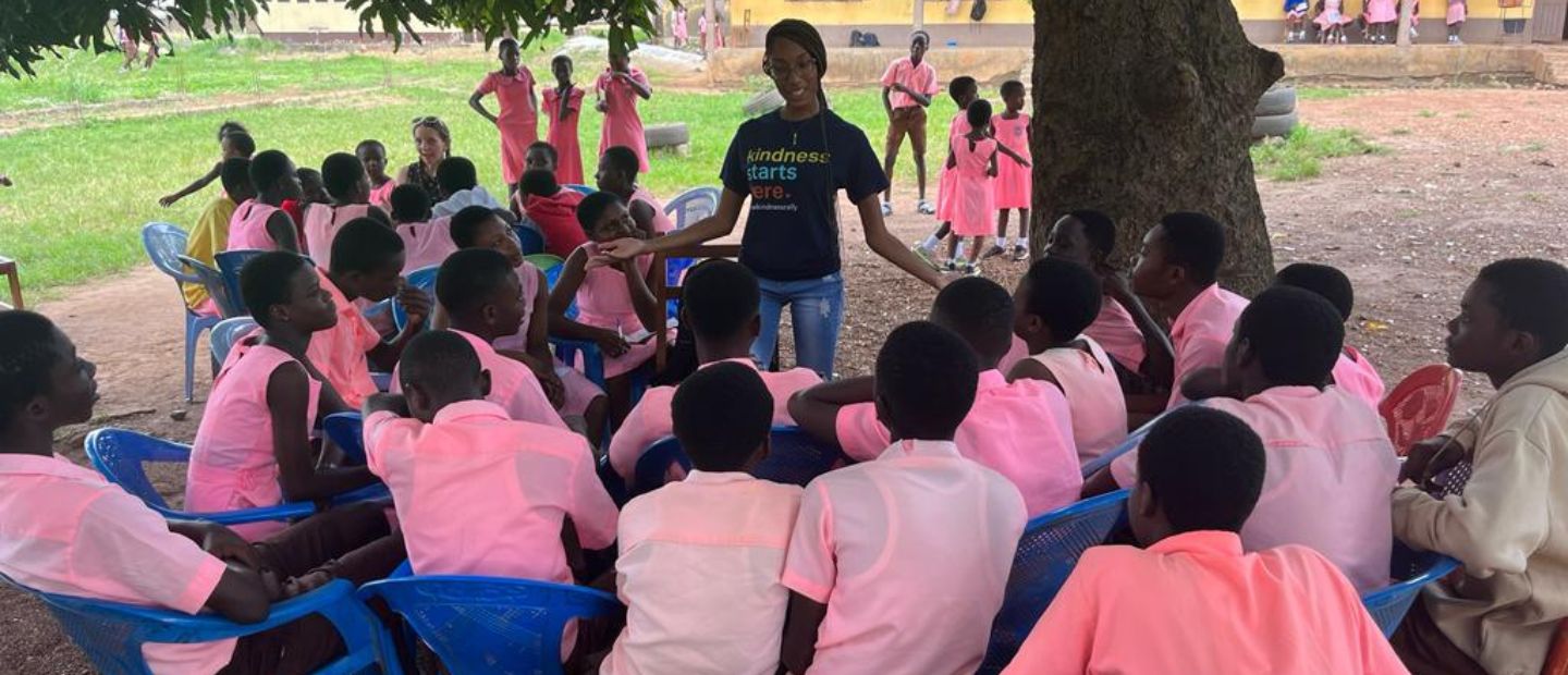 woman speaking to a group of kids A woman speaking to a group of kids in pink shirts outside.