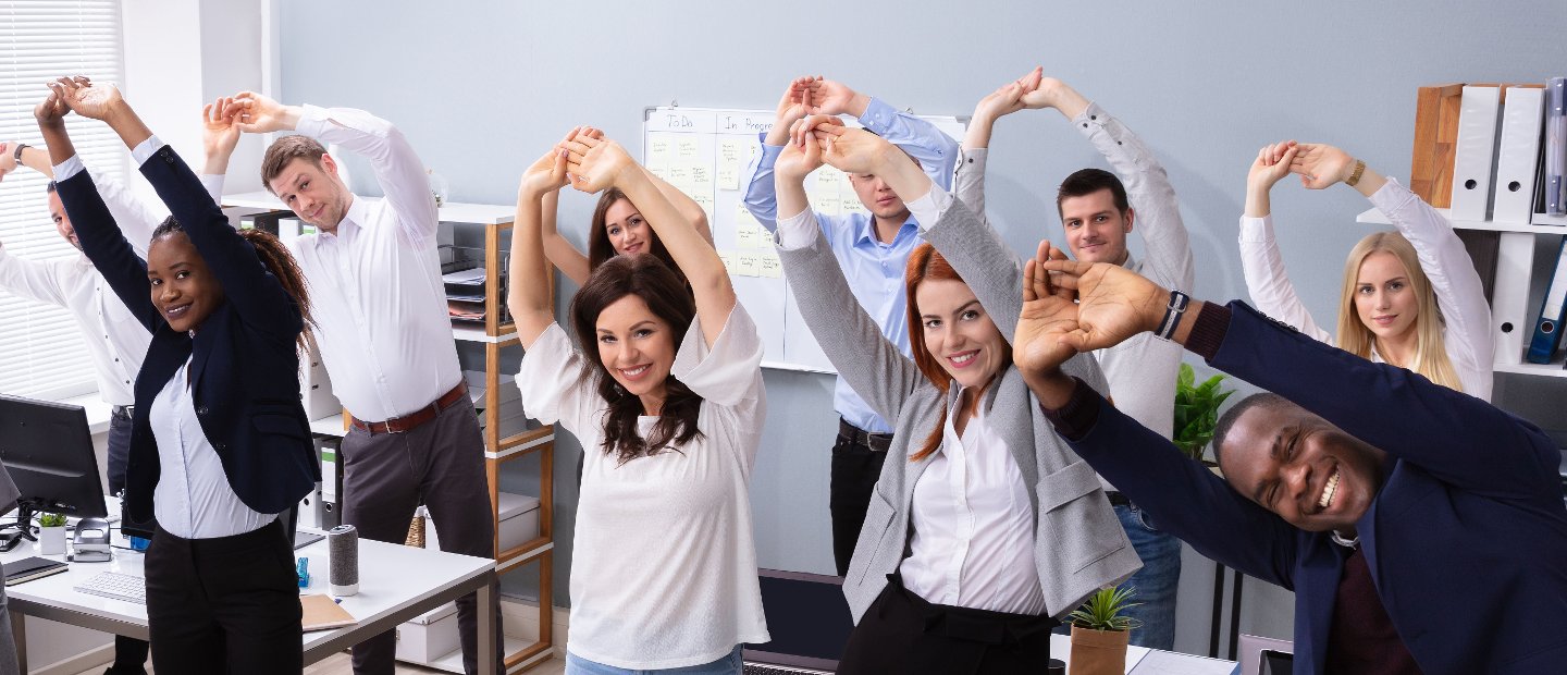 corporate wellness Staff in a corporate office performing a side bend stretch.
