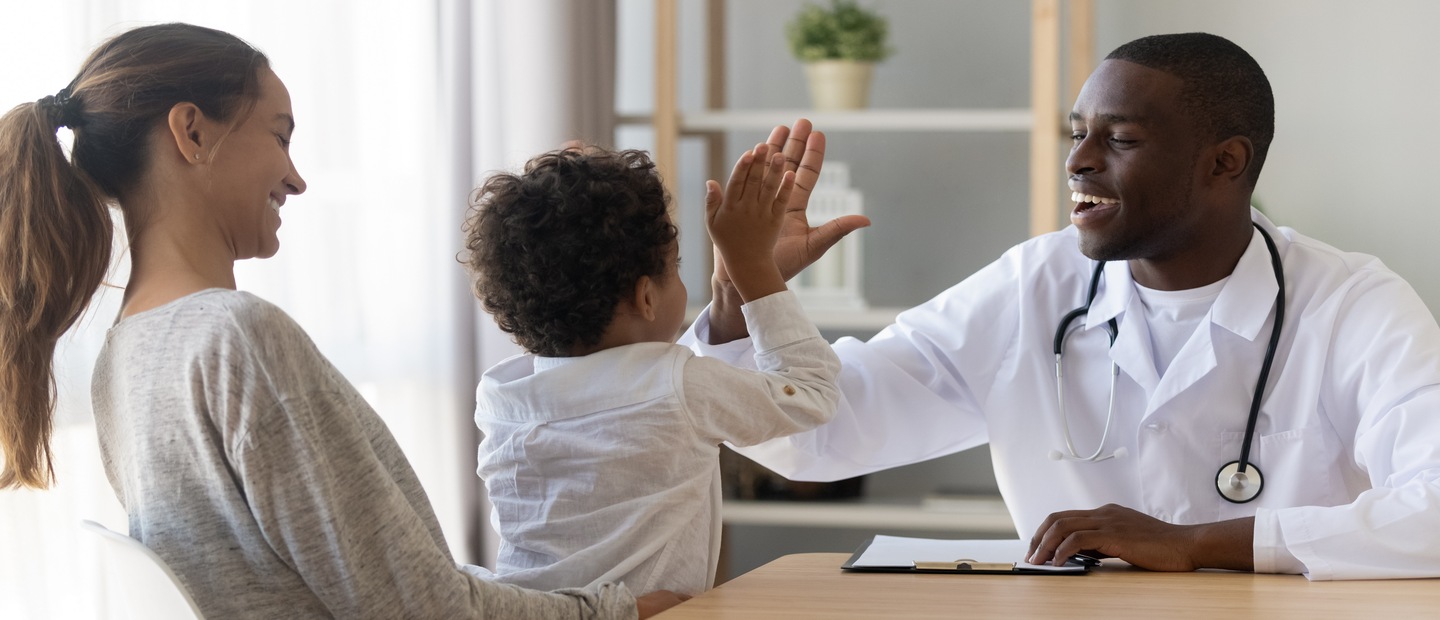 physician's assistant A physician's assistant giving a high five to a kid sitting in his mom's lap.
