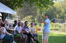 Person teaching group of people outside by a field and a tent