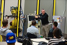 Students in a class observing a professor teach about mechanical equipment.