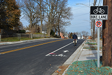a road with a person riding a bike in the bike lane with a bike lane sign