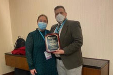A man and a woman holding an award plaque