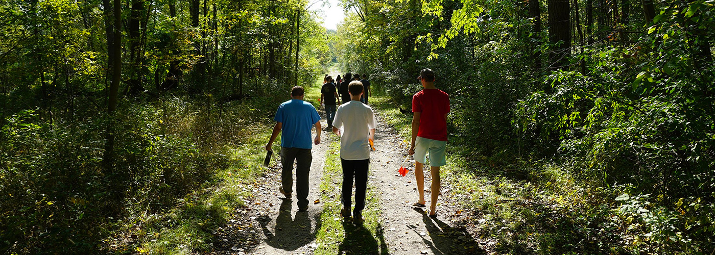 Three people walking down a nature path