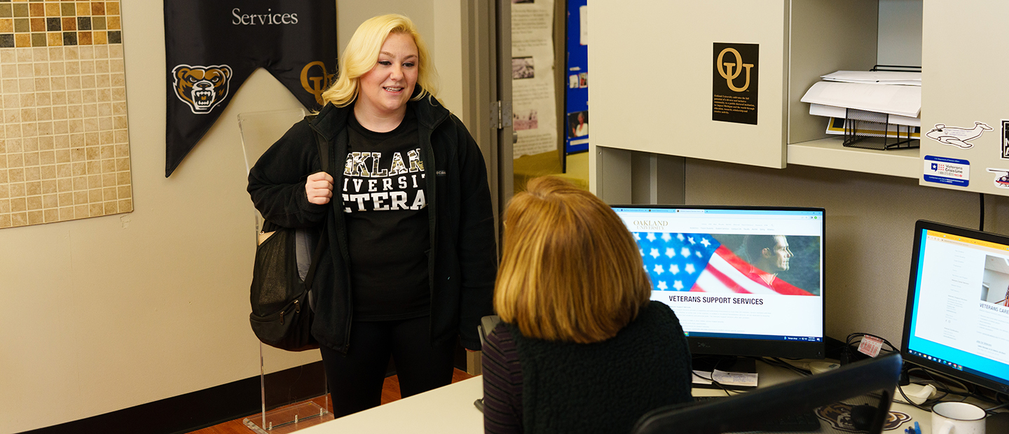 Current Student Banner Young Woman in Oakland University Veteran speaks to a woman in the Veteran Support Services office