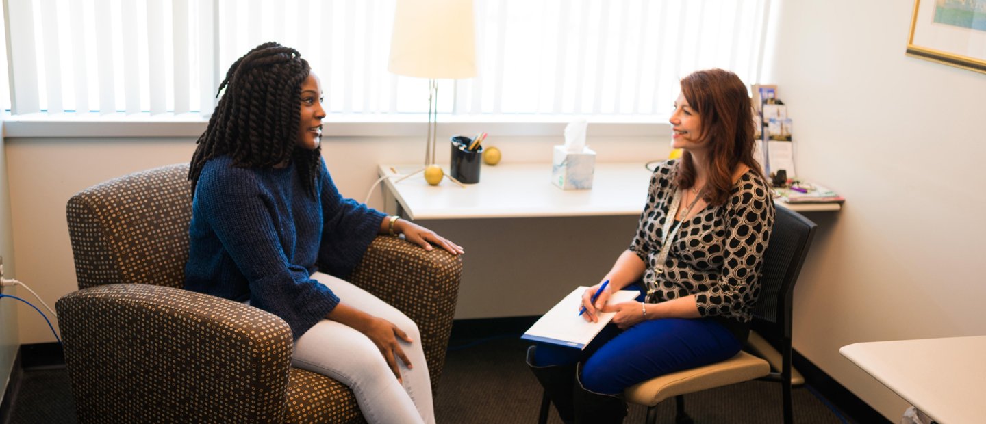_0001_PhD in Counseling.jpg Two women seated in an office, facing each other, smiling.