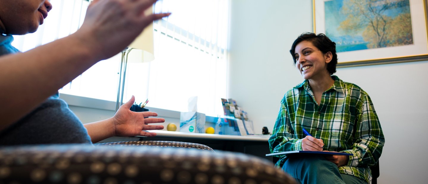 _0005_Licensing.jpg Two people seated in an office, facing each other, smiling and talking.