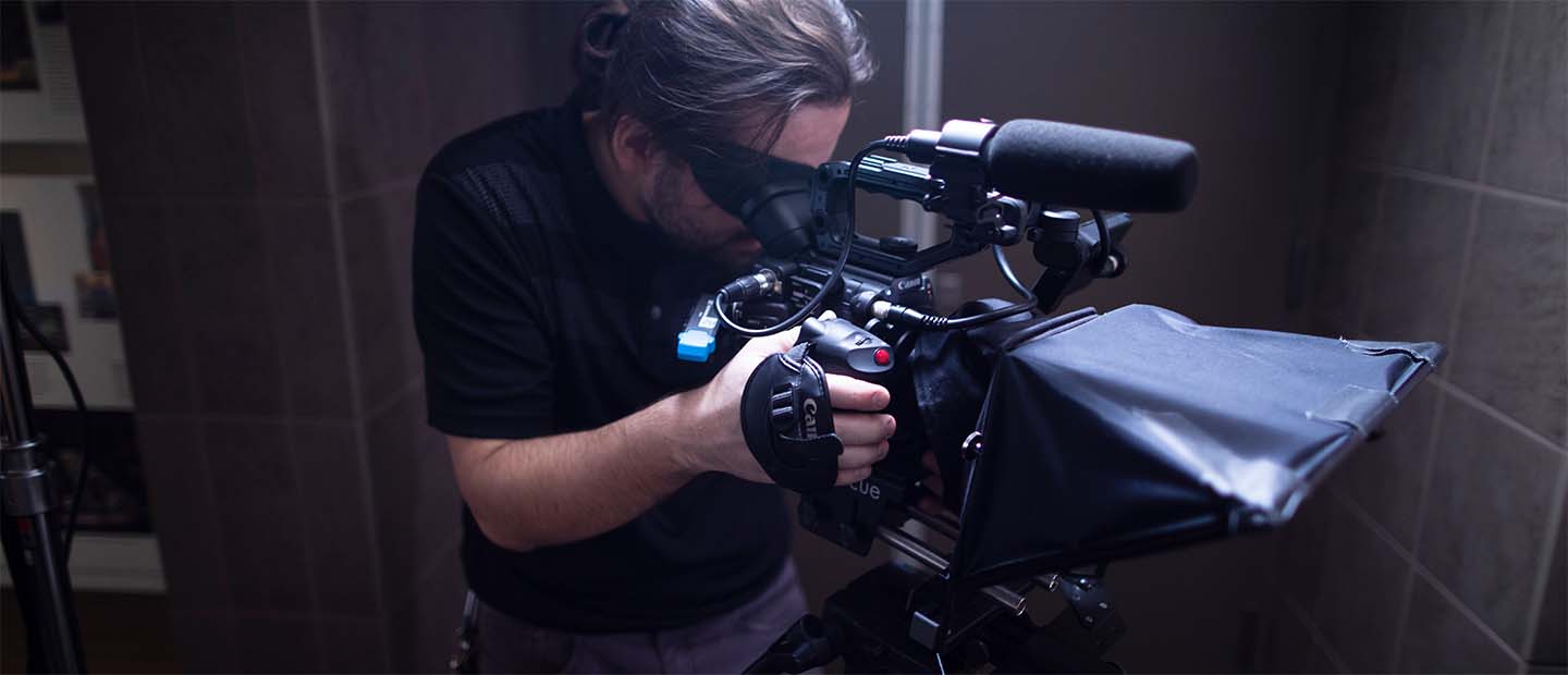 Live Streams Banner A man standing behind a video camera, filming.