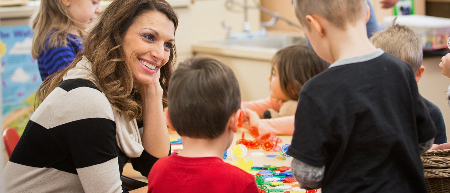 _0003_special-education_aba.jpg Woman sitting at table with a few kids