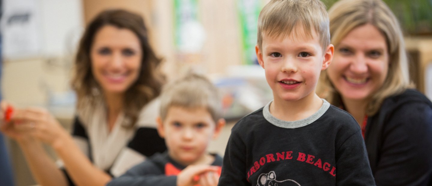 _0005_special-education_sld-endorsement.jpg kid looking at the camera with two women and one other kid in the background