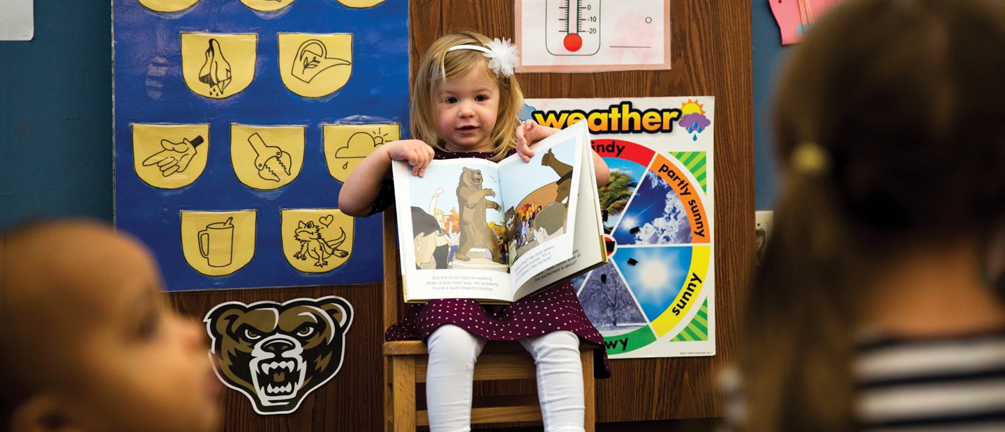 _0007_early-childhood-education.jpg Girl sitting on a chair holding up a book