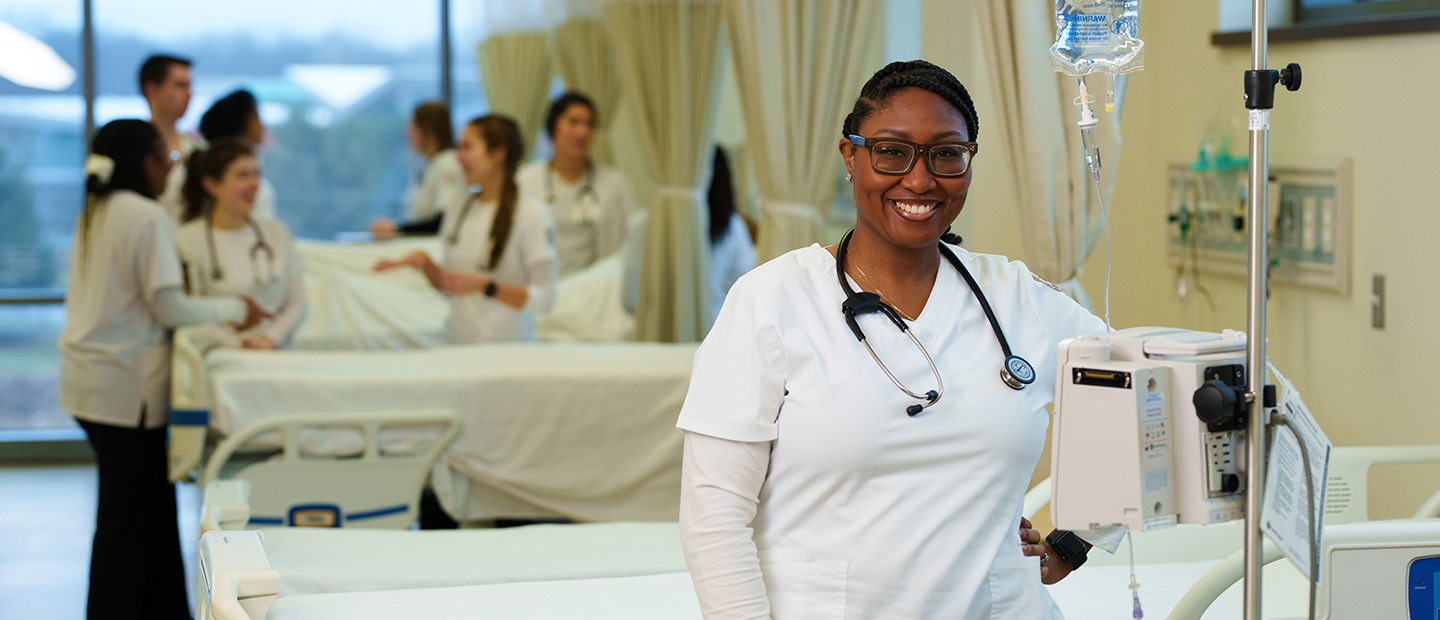 SON-25448_075 1440x620.png woman stadning in front of hospital bed smiling at camera
