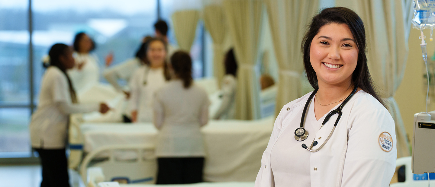 SON-25448_088 1440x620.png A nurse in a white lab coat, with a stethoscope around her neck, smiling at the camera.