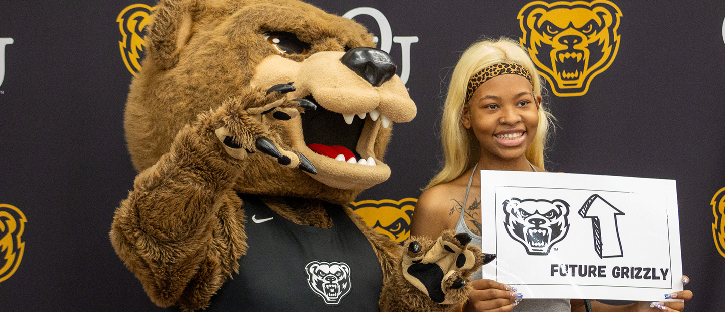 First-year student A new Oakland University student holding a Future Grizzly sign and posing with the Grizz mascot
