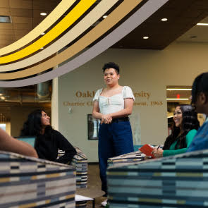 Person standing and people sitting around looking at them